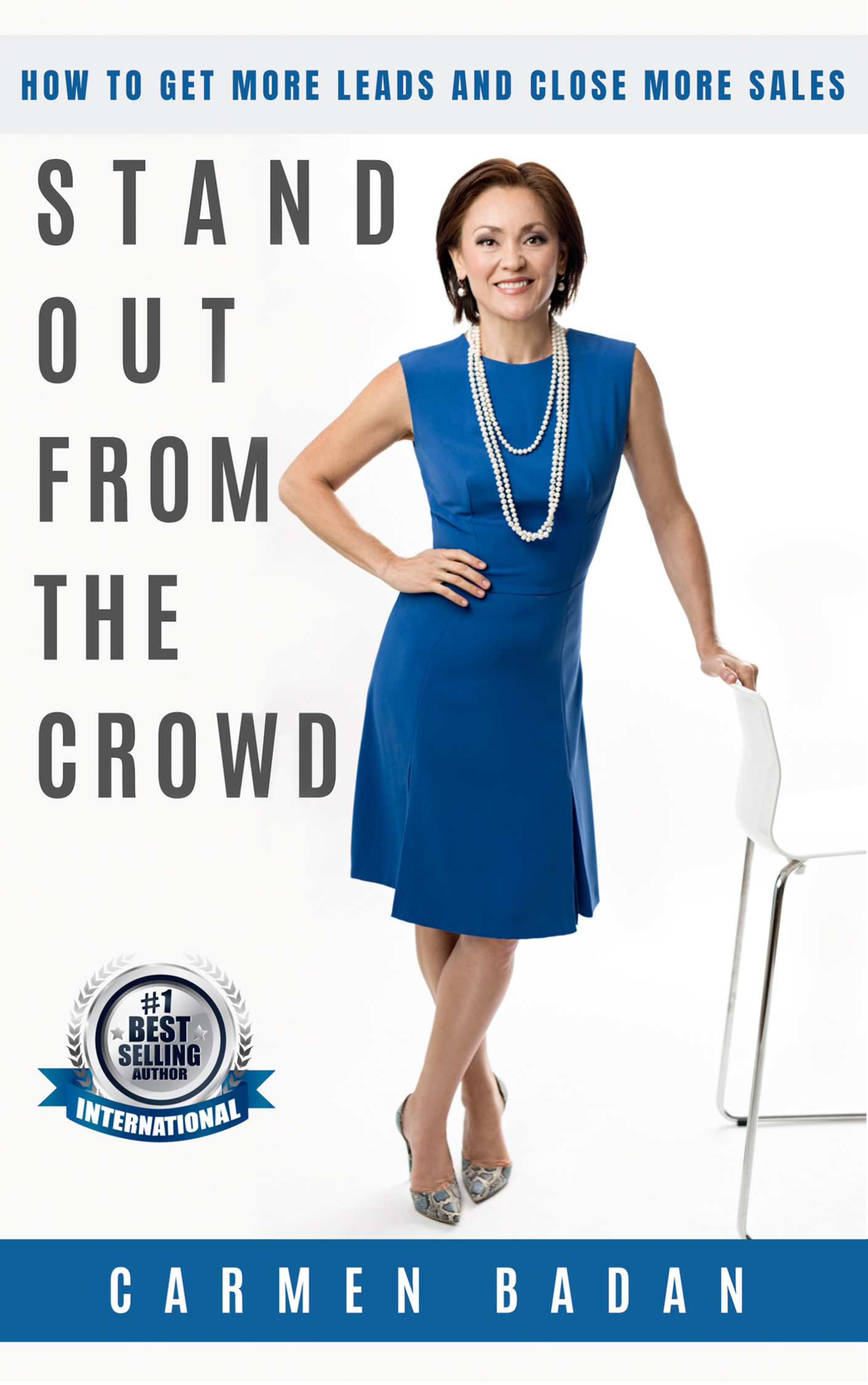Carmen Badan is standing in a blue fitted business dress with one hand resting on a white chair. Next to her in big bold letters is the title STAND OUT FROM THE CROWD. Above her, in a light gray rectangle, are the words HOW TO GET MORE LEADS AND CLOSE MORE SALES. At the bottom in a blue rectangle is CARMEN BADAN. Just above the rectangle, close to Carmen's feet is a logo that says #1 Best Selling Author International
